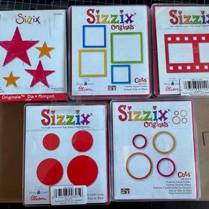 May include: A collection of Sizzix Originals die-cut sets. The sets include various shapes such as stars, squares, circles, and filmstrip designs. The packaging features the Sizzix logo and product information.