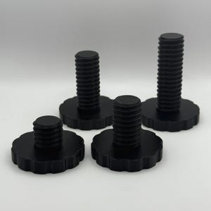 May include: Four black thumb screws with a ridged design on the threaded portion and a scalloped edge on the base. The screws vary in height, with the tallest measuring approximately 2 inches.