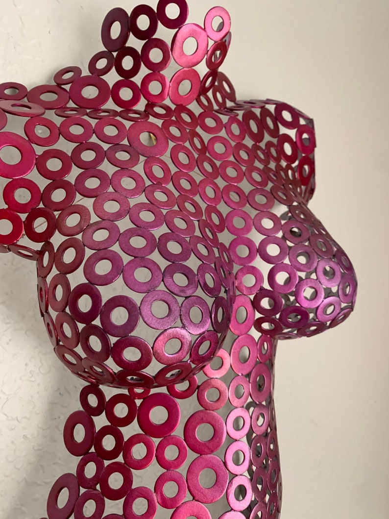 May include: A pink metal sculpture of a torso made from many small circles.