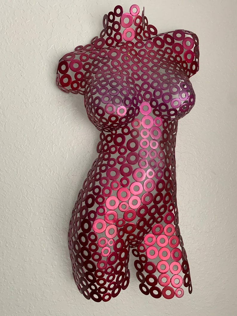 May include: A metal sculpture of a human torso made of hundreds of small, overlapping, metallic circles. The circles are a gradient of pink and red.