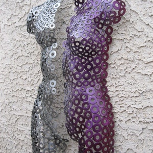 May include: Two metal sculptures of human torsos made from washers. The sculpture on the left is silver, and the sculpture on the right is purple.