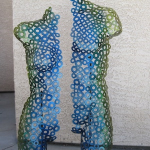 May include: Two abstract sculptures made of metal washers, one blue and green, the other green and blue. The sculptures are shaped like human figures.