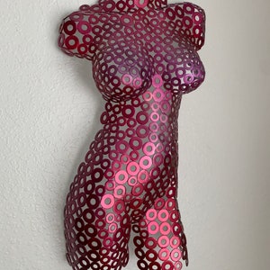 May include: A metal sculpture of a torso made from a collection of small, overlapping circles. The sculpture is painted in a gradient of pink and red.