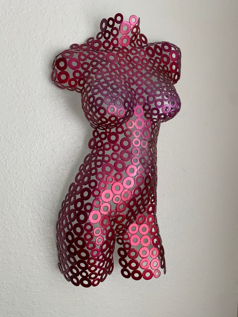 May include: A metal sculpture of a torso made from a collection of small, overlapping circles. The sculpture is painted in a gradient of pink and red.