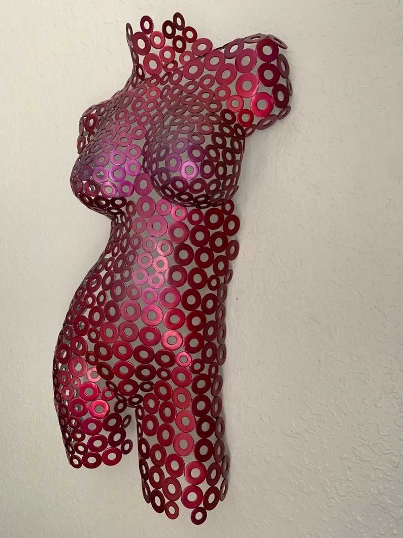 May include: A red metal sculpture of a human torso made from a collection of small, round metal washers.