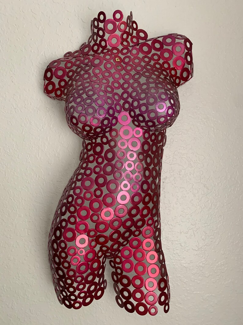 May include: A pink metal sculpture of a torso made of interlocking circles.
