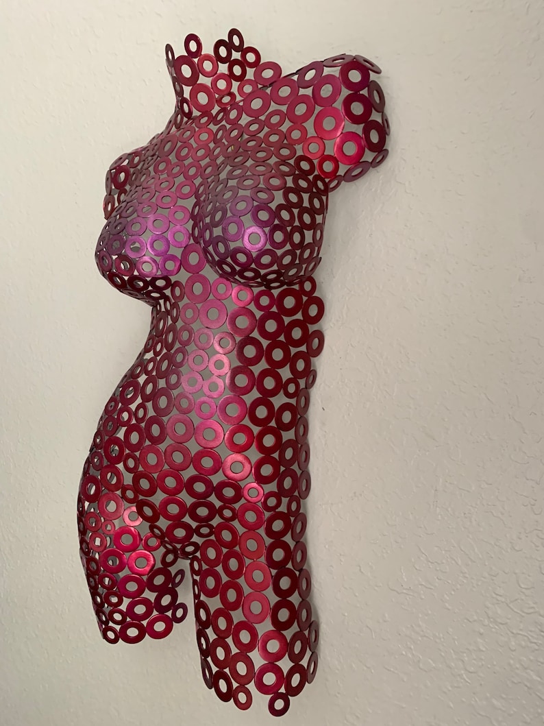 May include: A red metal sculpture of a human torso made from hundreds of small metal rings. The sculpture is abstract and has a modern design.