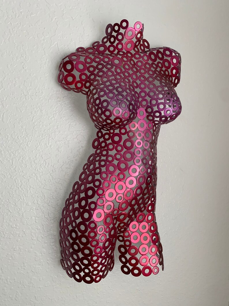 May include: A pink metal sculpture of a torso made from many small circles.