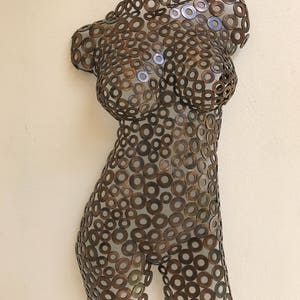 May include: A metal sculpture of a torso made from hundreds of small, round, copper-colored washers.