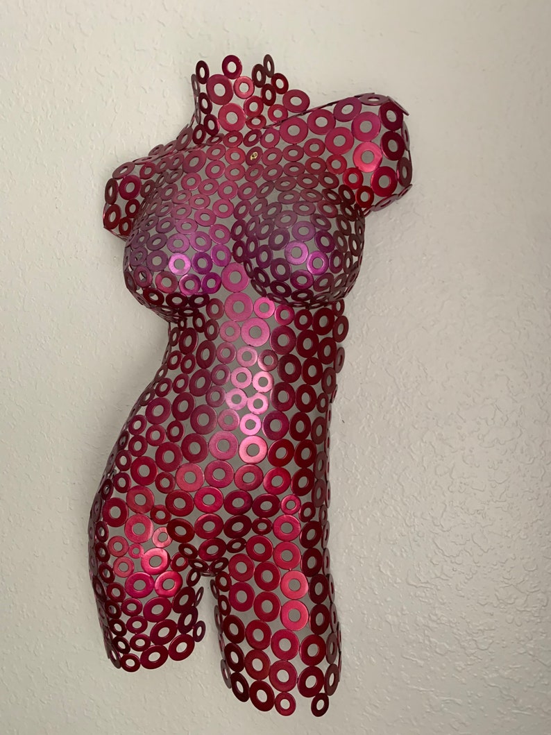 May include: A red metal sculpture of a torso made from many small circles.