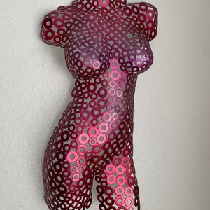 May include: A metal sculpture of a human torso made of small, overlapping circles. The sculpture is painted in shades of pink and red.