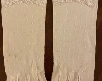 May include: A pair of white gloves with a beaded design. The gloves have a dotted pattern and a beaded trim at the top.