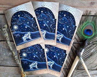 Könnte beinhalten: Eine Sammlung von Kunstdrucken mit einem Sternbild-Hasen-Design. Jeder Druck zeigt einen blauen Nachthimmel mit einem Sternbild-Hasen, der über einem weißen Hasen auf einem Hügel springt. Die Drucke haben einen dekorativen Rand.