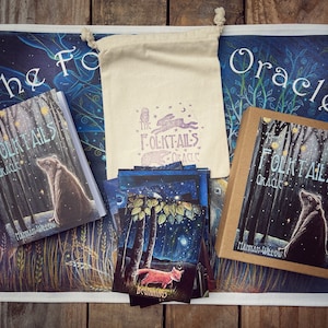 May include: A set of The Folktales Oracle cards, including a guidebook, a deck of cards, and a drawstring bag. The cards feature illustrations of woodland creatures and nature scenes. The guidebook and box are brown with white text. The bag is white with a black and white illustration of a rabbit, owl, and stars.
