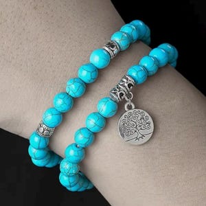 Peut inclure: Un bracelet à double rang de perles turquoise avec un pendentif en argent en forme d'arbre de vie.