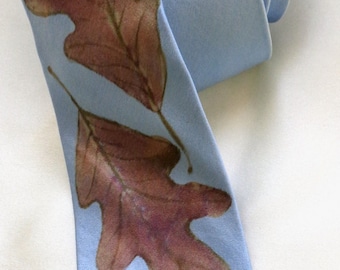 May include: A light blue silk tie with three brown oak leaves printed on it.