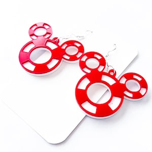 May include: A pair of red and white Mickey Mouse-shaped earrings. The earrings feature a red outline with white stripes and a white inner circle. The earrings hang from silver-colored hooks.