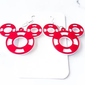 May include: A pair of red and white Mickey Mouse-shaped earrings. The earrings feature a circular design with a white center and a red outer ring. The earrings are made of a lightweight material and have silver-colored hooks.