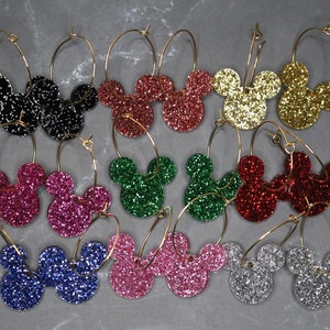 May include: A set of 10 pairs of gold hoop earrings with glitter Mickey Mouse head charms in various colors, including black, red, green, pink, blue, silver, and gold.
