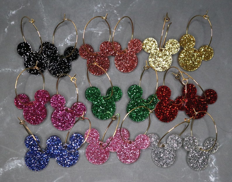 May include: A set of 10 pairs of gold hoop earrings with glitter Mickey Mouse head charms in various colors, including black, red, green, pink, blue, silver, and gold.