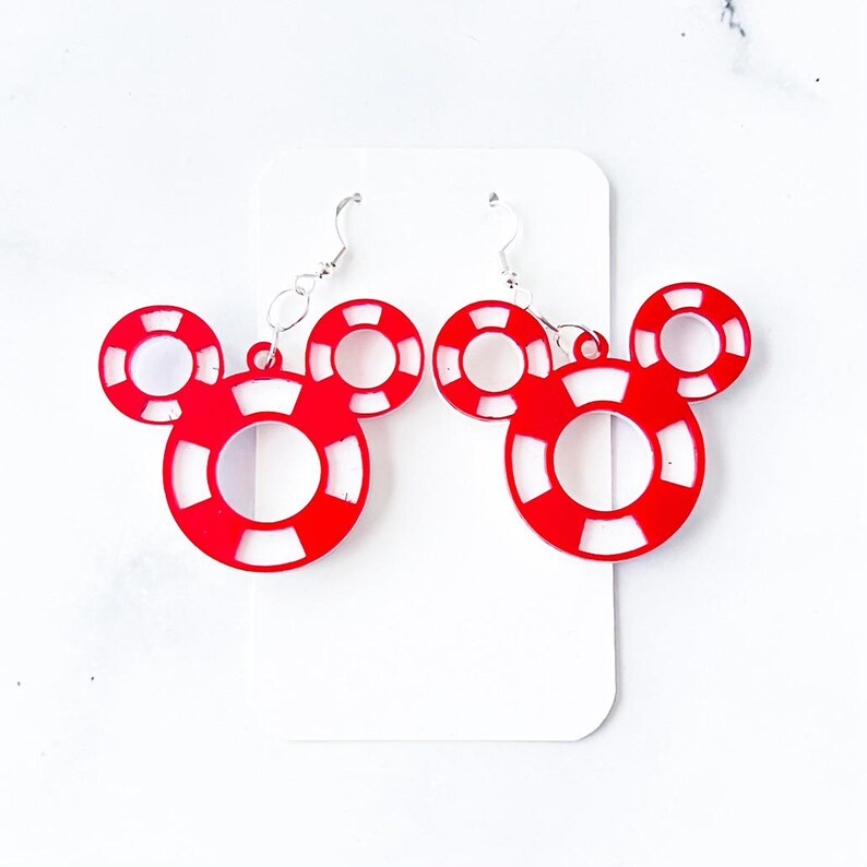 May include: A pair of red and white Mickey Mouse-shaped earrings. The earrings are made of red acrylic and feature a white inner circle and white stripes. The earrings hang from silver-colored fish hook ear wires.