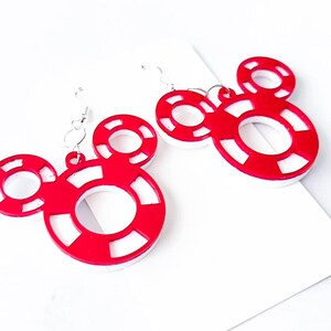 May include: A pair of red and white Mickey Mouse-shaped earrings. The earrings feature a circular design with a white center and red outer ring, connected by silver hooks. The earrings are on a white background.