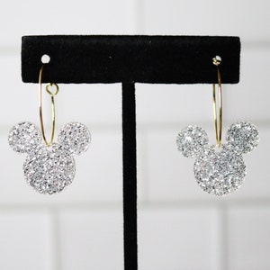 May include: A pair of silver glitter Mickey Mouse hoop earrings with gold hoops.