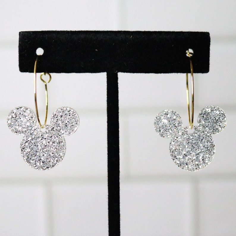 May include: A pair of silver glitter Mickey Mouse hoop earrings with gold hoops.