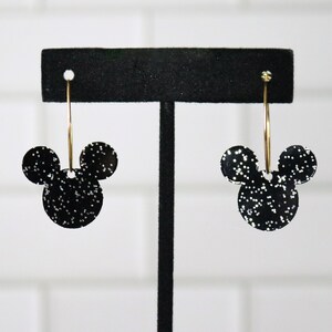 May include: Black glitter Mickey Mouse earrings with gold hoops.