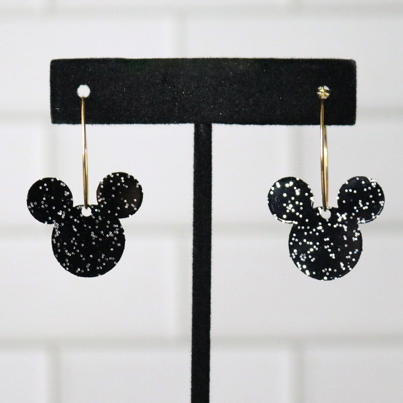 May include: Black glitter Mickey Mouse earrings with gold hoops.