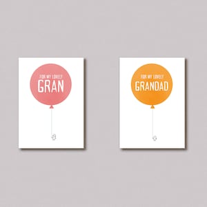 Puede incluir: Dos impresiones artísticas minimalistas sobre fondos blancos. Una presenta un globo rosa con el texto "FOR MY LOVELY GRAN", y la otra un globo naranja con "FOR MY LOVELY GRANDAD". Ambas tienen una pequeña figura debajo.