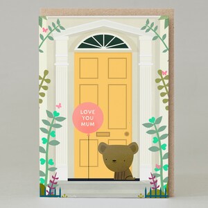 Puede incluir: Tarjeta de felicitación con una ilustración de una puerta amarilla. Un oso pardo asoma por encima de la puerta, sosteniendo un globo rosa con el texto "LOVE YOU MUM". La tarjeta está decorada con enredaderas verdes, mariposas rosas y una fachada arquitectónica blanca.