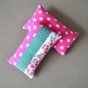 Op de afbeelding: Twee roze en witte kussens met patronen. Een kussen heeft een bloemenpatroon met groene accenten. Het andere kussen heeft witte stippen.