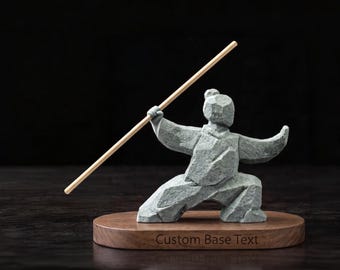 May include: A gray stone-textured figurine of a person in a martial arts stance holding a long, thin wooden staff. The figure is mounted on an oval wooden base with the engraved text Custom Base Text centered on the front edge of the wood.