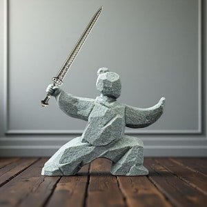 May include: A grey stone sculpture of a martial artist in a fighting stance, holding a detailed silver sword. The figure is on a wooden surface, with a grey wall in the background. The sword has an intricate design.
