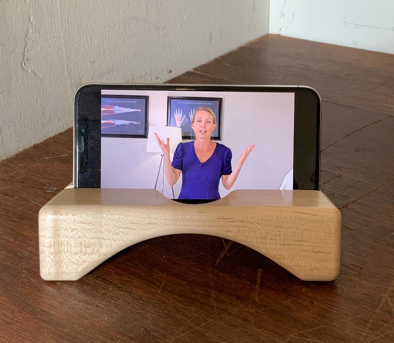 Wooden iPhone stand supports iPhone in landscape.