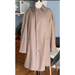 May include: A long, brown wool coat with a collar and button closure. The coat has a classic, tailored look.