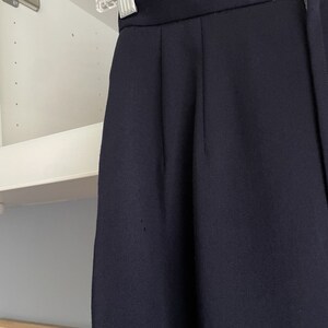 K&ouml;nnte beinhalten: Eine dunkelblaue, hochgeschnittene Hose aus glattem, strukturiertem Stoff.
