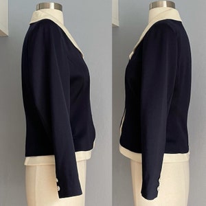 K&ouml;nnte beinhalten: Ein marineblauer Blazer mit wei&szlig;em Kragen und Manschetten. Der Blazer hat eine figurbetonte Silhouette und lange &Auml;rmel.