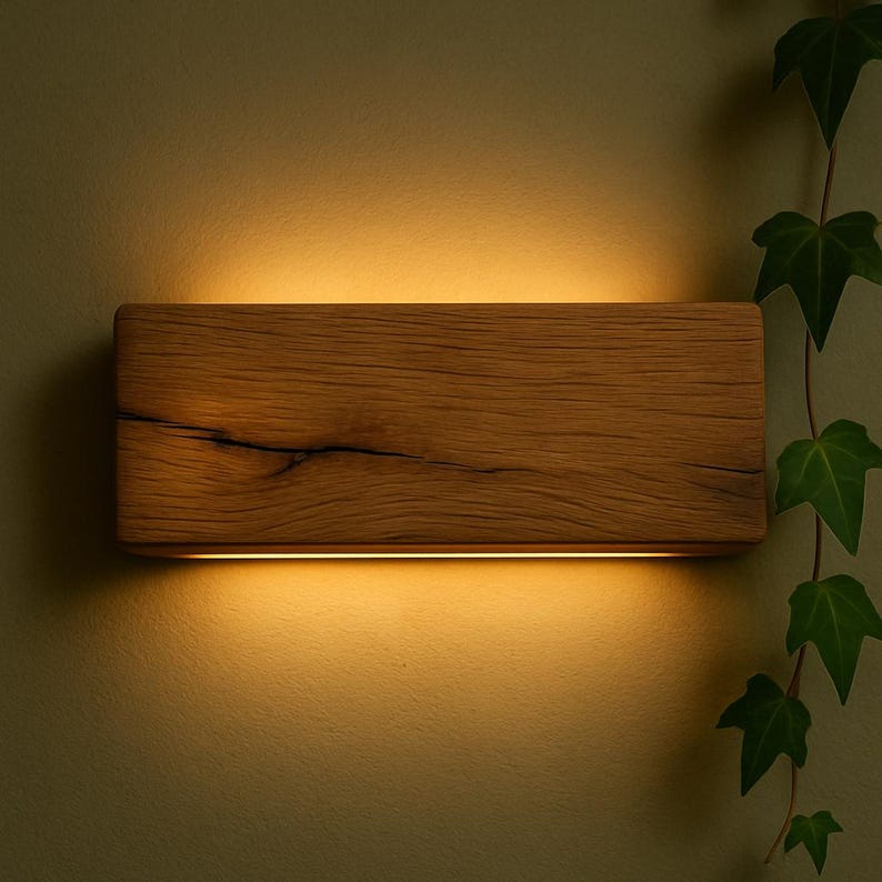 Peut inclure: Applique murale rectangulaire en bois, d&eacute;gageant une lumi&egrave;re chaleureuse. Le bois naturel r&eacute;v&egrave;le son veinage et sa texture. Une fine bande lumineuse horizontale &eacute;claire le mur en dessous. Du lierre vert ajoute une touche naturelle.