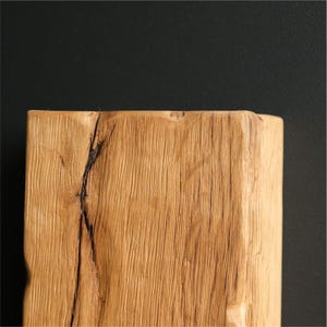 May include: Close-up of a light brown wooden beam with a natural wood grain pattern and a dark crack running through the center.