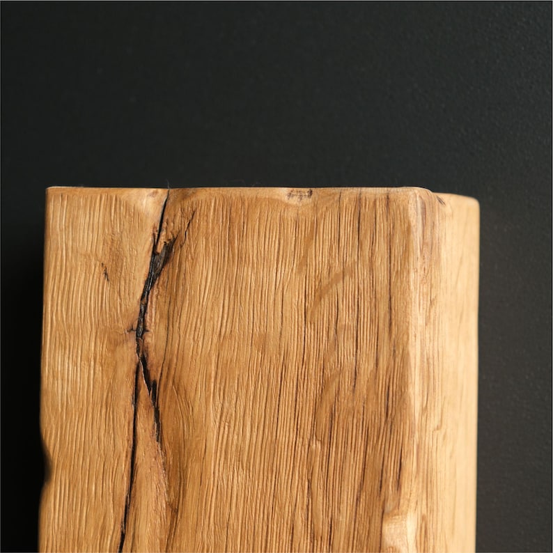 May include: Close-up of a light brown wooden beam with a natural wood grain pattern and a dark crack running through the center.