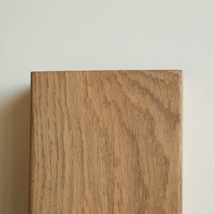 Op de afbeelding: Een close-up van een lichtbruin houten plank met een natuurlijk houtnerfpatroon.