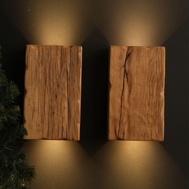 May include: Two rustic wooden wall sconces with warm light emanating from behind them. The sconces are made of reclaimed wood with a natural finish.