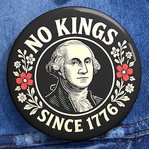 May include: A circular black badge featuring a portrait of George Washington, surrounded by the text "NO KINGS SINCE 1776". The design incorporates red and white floral elements, set against a denim jacket.