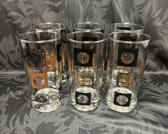 May include: Set of six clear glass tumblers with a gold and black geometric pattern. The glasses have a square design and are perfect for serving drinks.