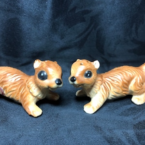May include: A pair of brown ceramic squirrel salt and pepper shakers. The squirrels are facing each other and have black eyes and noses.