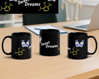 Könnte beinhalten: Drei schwarze Kaffeetassen mit dem weißen Schriftzug "Sweet Dreams", einer gelben chemischen Struktur und Illustrationen von Propofol-Fläschchen. Die Tassen stehen auf einer hellbraunen Oberfläche.
