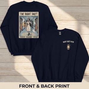 May include: Navy blue sweatshirt with a front graphic featuring a nurse with a lantern in a hallway, the text "THE NIGHT SHIFT", and the words "STRENGTH - ENDURANCE - CAFFEINE". The back has the text "NIGHT SHIFT CREW" and a lantern graphic.