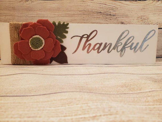 Shelf sitting sign with the word Thankful in galvanized metal and a rust felt flower with green center with felt leaves burlap and twine.